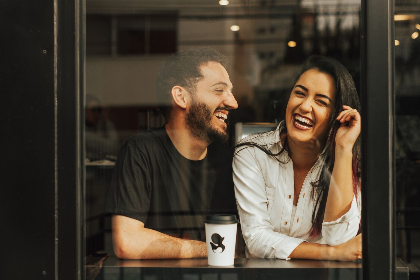 A couple laughing together at a café table
